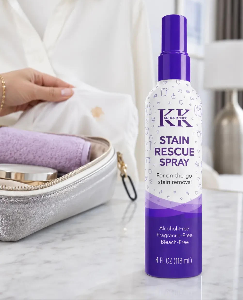 Knock Knock Stain Rescue Spray bottle on a marble vanity beside a white shirt and travel case
